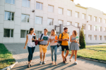 Five friendly students are walking after they passed test outside the college building and discuss the project