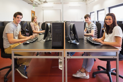 Happy students in computer room in college