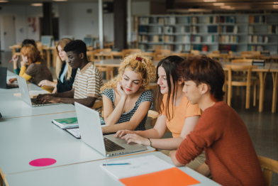 Multiracial young students using netbooks in library