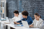 row-three-contemporary-serious-students-co-working-front-laptops-while-sitting-by-desk