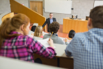 Elegant teacher with students sitting at the college lecture hall