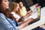 Young woman studying with laptop computer on white desk.